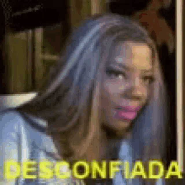 a woman with long hair and pink lipstick is making a funny face with the words `` desconfiada '' behind her .