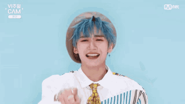 a young man with blue hair and a hat and tie is smiling .