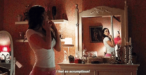 a woman is standing in front of a mirror and saying " i feel so scrumptious " .
