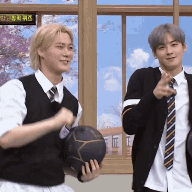 two men are standing next to each other and one is holding a basketball and the other is pointing
