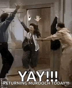 a group of people are jumping in the air in front of a door with their hands in the air .