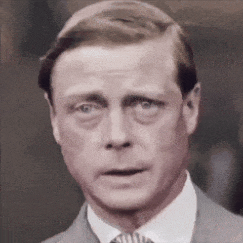 a man in a suit and tie looks at the camera with a surprised look on his face