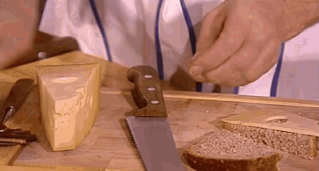 a person is cutting bread with a saw on a wooden cutting board