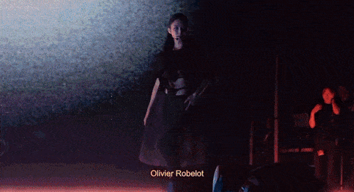 a woman stands in front of a screen that says olivier robelot on it