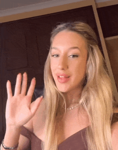 a woman with blonde hair is waving her hand