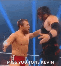 two men are wrestling in a ring and one of them is holding the other man 's hand .