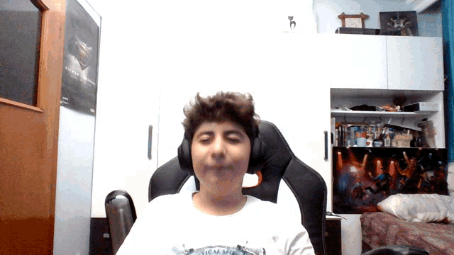a boy wearing headphones is sitting in a chair with a poster on the wall that says ' avengers ' on it