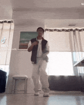 a man is dancing in a living room with a picture on the wall .