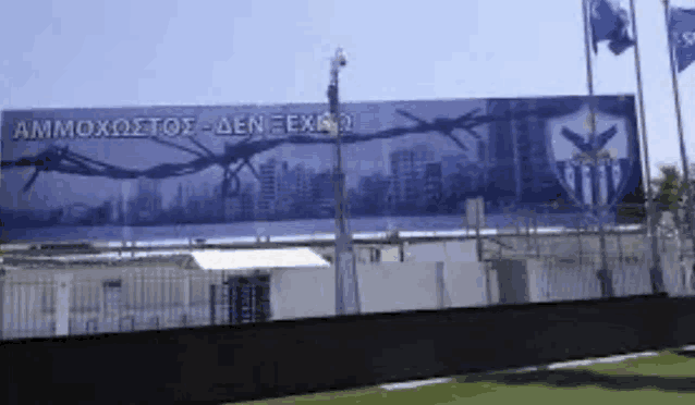 a large billboard with barbed wire on it says ammoxostos-den exiko