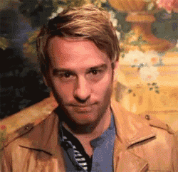a man in a brown leather jacket is making a funny face