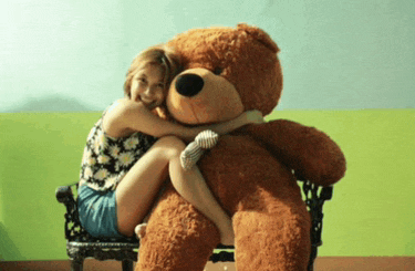 a woman is sitting on a bench hugging a giant teddy bear