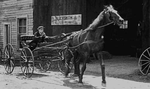a black and white photo of a horse drawn carriage in front of a sign that says blacksmith & co.