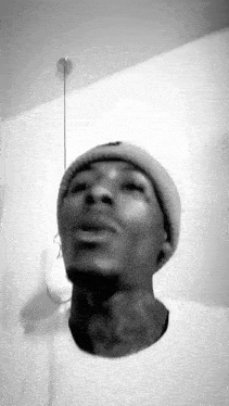 a man wearing a beanie and a white shirt is looking up .