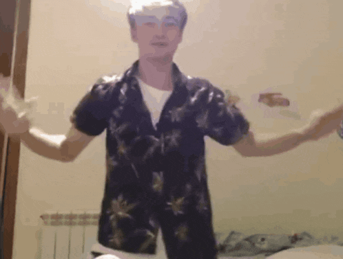 a man in a hawaiian shirt is dancing with his arms outstretched .