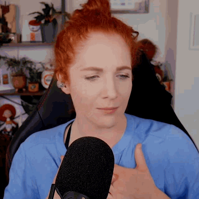 a woman with red hair is sitting in front of a microphone giving a thumbs up
