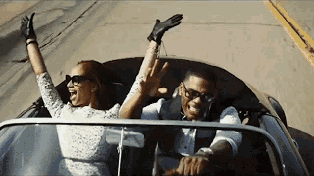 a man and a woman are riding in a car with their hands in the air