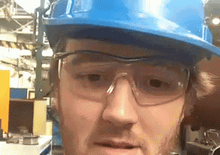 a man wearing a blue hard hat and safety glasses .