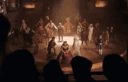 a group of people are standing on a stage in a dark room .