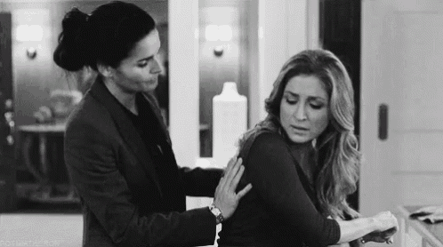 a black and white photo of a woman hugging another woman .