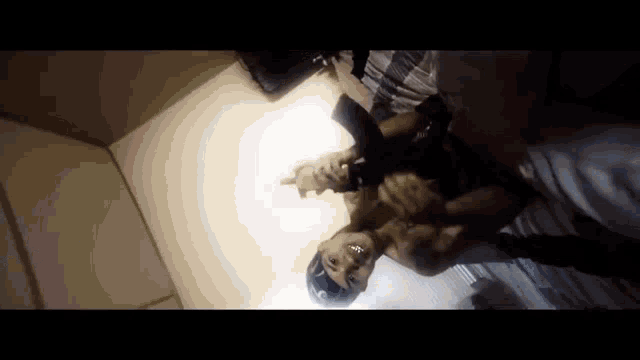 a man is holding a gun in a room with another man .