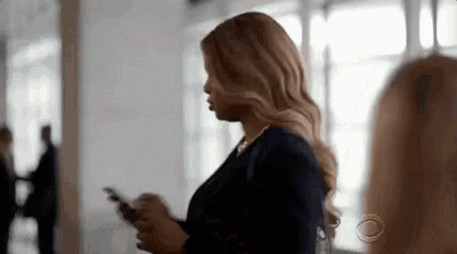 a woman is standing in a hallway while looking at her cell phone .