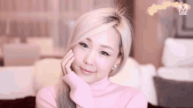 a woman wearing a pink sweater with the letter m on the bottom right