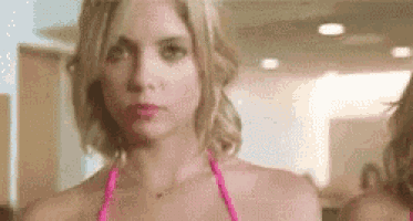 a woman in a pink bikini is standing in front of a mirror looking at herself .