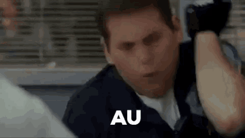 a man in a suit and tie is standing in front of a window and a sign that says au .