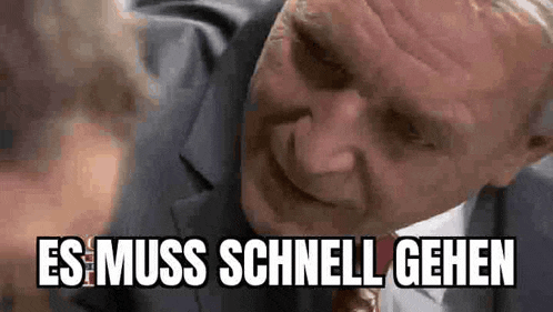 a man in a suit and tie is talking to another man and the words es muss schnell gehen are above him .