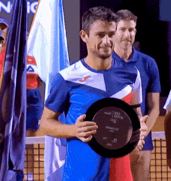 a man in a blue shirt is holding a trophy that says big open