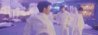 a group of men in white shirts and pants are standing on a street .