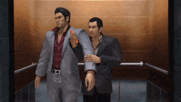two men in suits are standing in an elevator and one is holding a red object