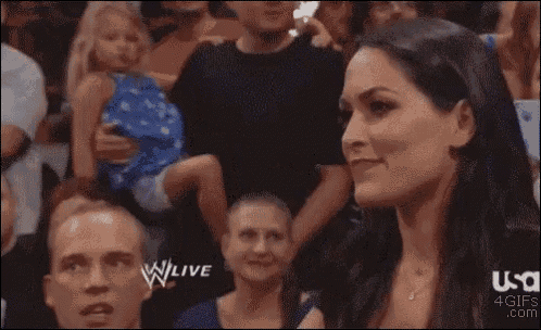 a man and a woman are watching a wrestling match and the woman is holding a baby .