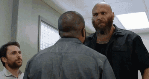 a bald man with a beard is talking to another man