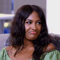 a woman in a green shirt is making a funny face while sitting on a couch .