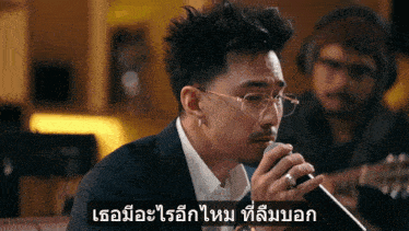 a man wearing glasses is singing into a microphone with a caption in another language