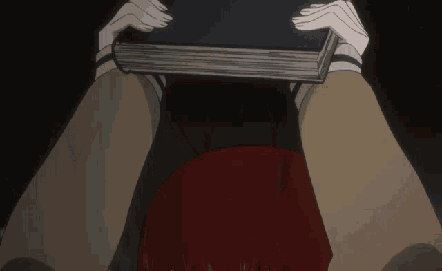a person with red hair is holding a book in front of their face