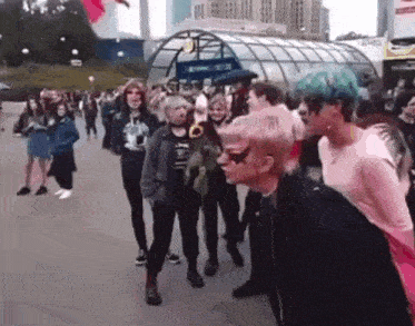 a group of people are standing in front of a building . one of the people is wearing a mask .