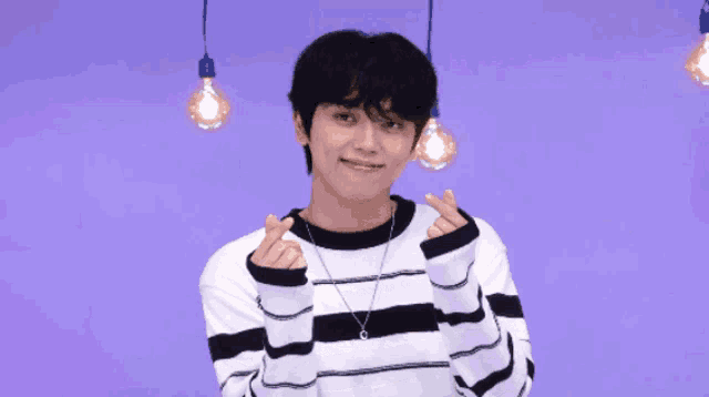a young man in a striped sweater making a heart with his hands