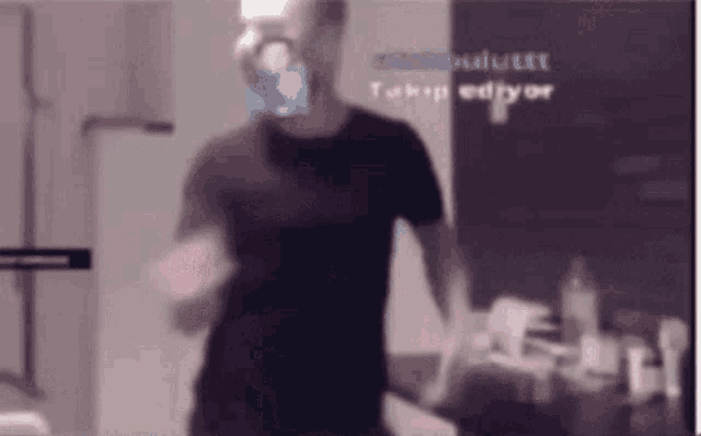 a man in a black shirt is standing in front of a wall with a sign that says ' takip ediyor ' on it