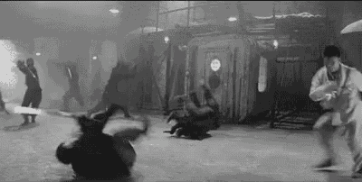 a black and white photo of a group of people practicing martial arts in a room .