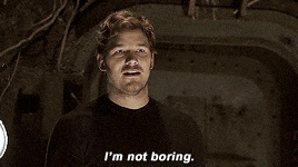 a man says " i 'm not boring " while standing in a dark room
