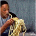 a man is eating noodles with a fork and spoon .