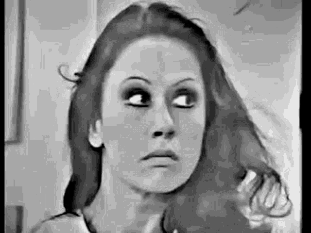 a woman is looking at her hair in a mirror and making a funny face .