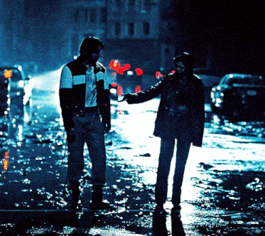 a man and a woman are walking down a wet street