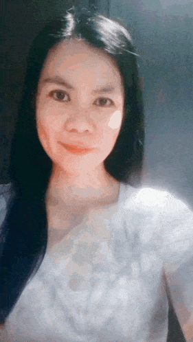 a woman with long black hair and a white shirt is smiling
