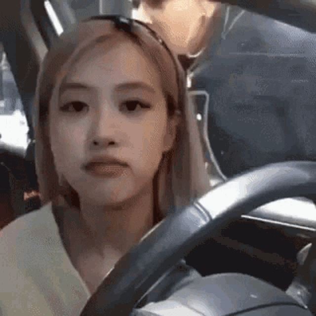 a woman is sitting in the driver 's seat of a car with a man behind her .