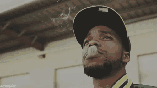 a man wearing a hat is smoking a cigarette with the name akistayder written below him