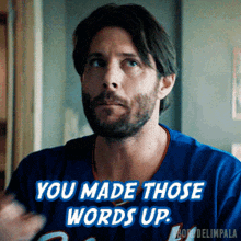 a man with a beard is wearing a blue jersey that says " you made those words up "