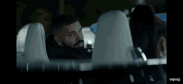 a man with a beard is sitting in the back seat of a car with the word vevo on the bottom right